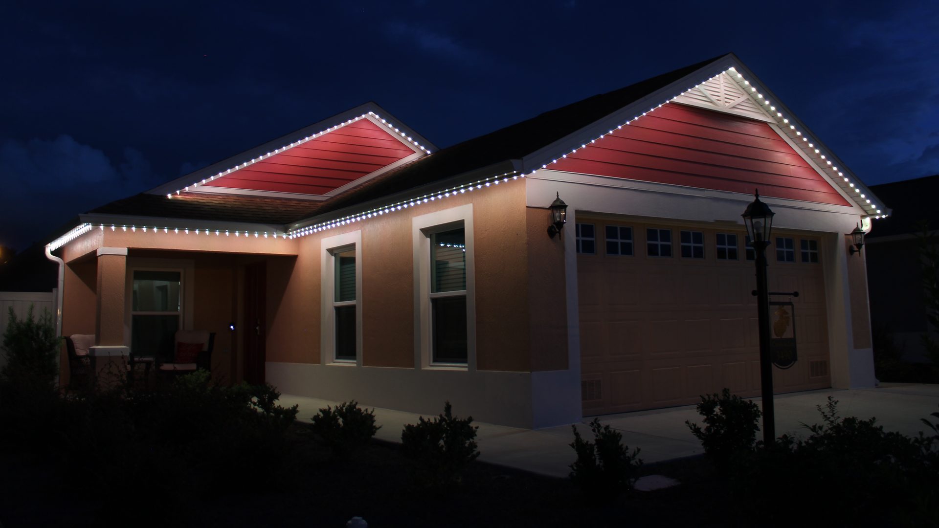 Trimlight permanent roofline lights in warm white on a Villages home at dusk
